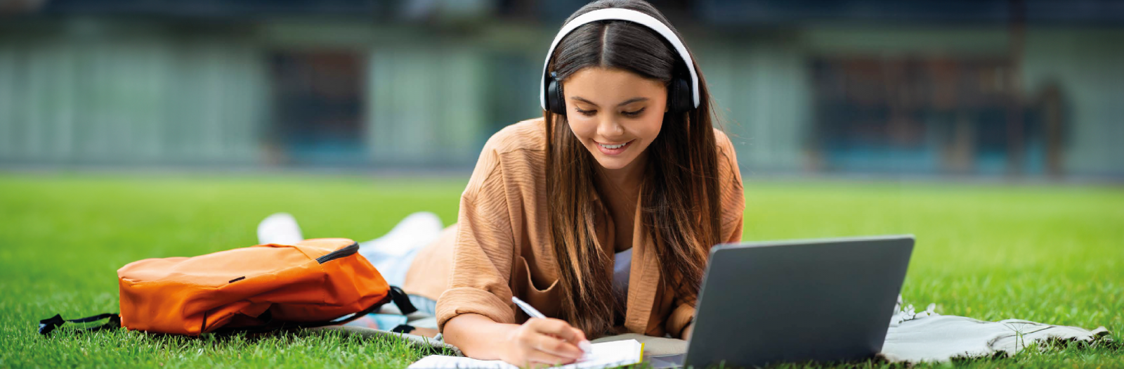 Studentessa che studia ascoltando la musica in un prato