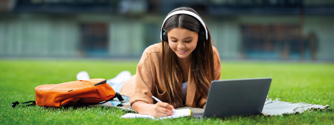 Studentessa che studia ascoltando la musica in un prato