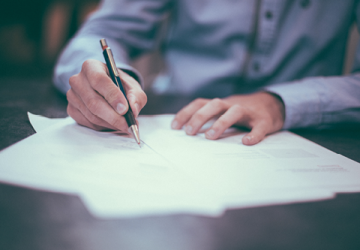 Uomo seduto a una scrivania mentre firma documenti 