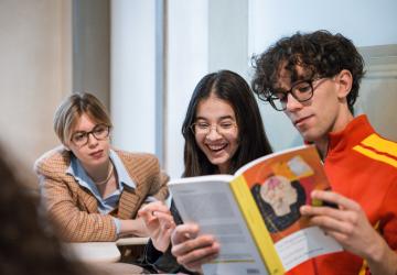 Ragazze e ragazzo con un libro di testo in mano