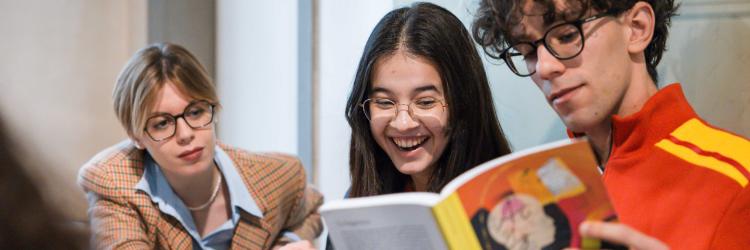 Ragazze e ragazzo con un libro di testo in mano